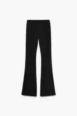 Pantalón negro de tiro alto, confeccionado en tejido elástico con corte ajustado hasta la rodilla y acampanado en el bajo.