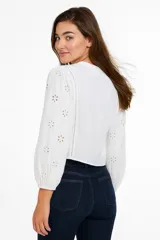 Camisa blanca de algodón con bordado tipo broderie, corte al cuerpo, cuello en V y cierre frontal con botones.