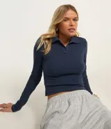 Blusa azul marino de rib de algodón con cuello polo y mangas largas.