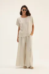 Pantalón palazzo de lino color blanco, con cintura elastizada y botones decorativos en los laterales.