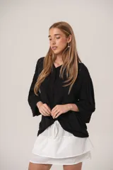 Camisa negra con textura de bolitas, manga globo y cuello camisero.