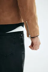 Campera de gamuza color camel, con cuello camisero, cierre frontal y bolsillos laterales con cierre. Presenta un corte estándar y forro interior.