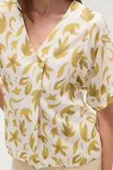 Blusa marrón con estampado de hojas color crema, cuello en V y mangas cortas. Corte holgado.