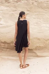 Vestido corto negro sin mangas, con corte evasé y detalle de volado en el ruedo.