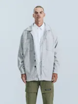 Campera gris melange de paño con cuello camisero, cierre frontal con botones a presión, bolsillos frontales y corte recto.