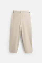 Pantalón gris de corte ancho con cintura elástica, pliegues frontales, bolsillos laterales y traseros de vivo. Incluye detalle de hebilla metálica en la trabilla y cierre frontal con cremallera y botón.