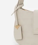 Cartera baguette pequeña color marrón con textura en relieve, correa ajustable, cierre con cremallera y solapa con detalle de colgante.