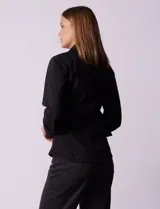 Camisa negra de algodón con cuello con solapa, abertura central con botones, delantera tableada y mangas 3/4. Laterales elastizados.