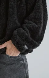Hoodie negro oversize con cierre central al estilo anorak, confeccionado en piel de corderito sintético. Capucha ajustable con cordón y bolsillo canguro.