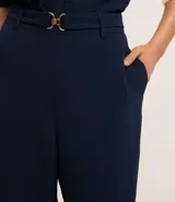 Pantalón zanahoria de cintura alta, confeccionado en tejido airflow color azul marino, con trabillas, cintura elástica y hebillas metalizadas.