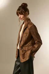 Blazer de poliéster con estampado animal print en tonos marrones y negros, de corte holgado, con cuello solapa y cierre frontal de doble botonadura.