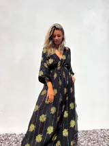Vestido túnica largo negro con estampado dorado de flores y rayas verticales.