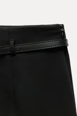 Pantalón culotte color crema, de tiro medio y pierna ancha. Incluye cinturón marrón con hebilla metálica.