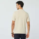 Chomba de piqué de algodón color beige con cuello clásico y tapeta de dos botones.