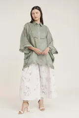 Camisa blanca de lino con corte amplio, cuello camisero y mangas 3/4 con detalle de puntilla en el borde.