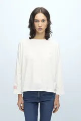 Remera blanca de manga larga con cuello redondo y pequeño logo estampado en el pecho y en la manga.