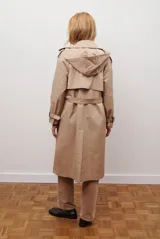 Trench coat largo color beige con doble botonadura, cuello solapa, cinturón ajustable y puños con tiras.