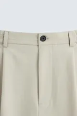 Pantalón de vestir color beige, corte wide fit, con cintura elástica, pliegues frontales, bolsillos laterales y traseros de vivo.