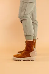 Bota de caña media color marrón óxido, confeccionada en cuero gamuzado. Presenta cierre frontal con cremallera, suela track color beige y detalle de pieza de cuero en la parte trasera del tobillo.