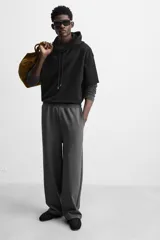 Pantalón jogger wide fit color gris oscuro, confeccionado en tejido de algodón compacto con elasticidad. Cuenta con cintura elástica ajustable con cordón, pliegues frontales, bolsillos delanteros y bolsillo trasero de parche.