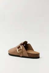 Zuecos negros con base de corcho, puntera cerrada y hebilla dorada decorativa.