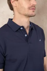 Chomba azul con cuello clásico, tapeta de dos botones y logo bordado en el pecho.