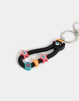 Llavero con dije de celular negro con teclado numérico y pantalla con la frase "Miss U". Incluye un strap de resorte negro con cuentas de colores y un dije con forma de cara.