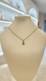 Collar con cadena dorada y dije de amatista en forma de lágrima.