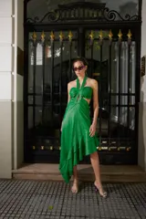 Vestido midi de cuero sintético color verde, con escote halter, cut-outs laterales y falda asimétrica con volados.