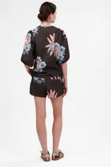 Camisa de manga corta abullonada con cuello mao y estampado de tigres y flores en tonos naranja, azul y rosa sobre fondo gris.
