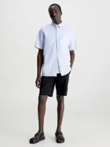 Camisa celeste de popelín de algodón superelástico, con cuello en punta, manga corta, tapeta con botones y logo con monograma de Calvin Klein en el pecho.