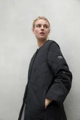 Campera acolchada color beige con patrón de rombos, cuello redondo y cierre con botones a presión.