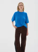 Remera de punto negra con cuello redondo y mangas cortas. Presenta un diseño de tejido con trenzas verticales.