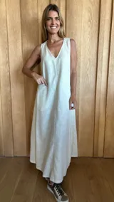 Vestido largo color crudo, sin mangas y con escote en V. Presenta aberturas laterales en el ruedo y bolsillos laterales a la altura de la cadera.