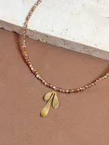 Collar corto de cuentas facetadas tornasol con dije colgante dorado con forma de hojas.