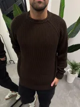 Sweater de punto marrón con cuello redondo y mangas raglán.