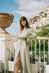 Vestido camisero midi color verde claro, con cuello solapa, escote pico, manga larga remangada con trabilla y botón, bolsillos delanteros de plastrón, cintura elástica, cierre frontal con botones y cinturón de rafia trenzada con hebilla redonda.
