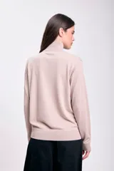 Polera beige de cuello alto y mangas largas.