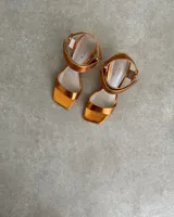 Sandalias plateadas con tira delantera, tobillera con hebilla y taco geométrico.