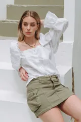 Minifalda de jean azul con corte en A y bolsillos tipo cargo con solapa y botón. Tiene un chaleco haciendo juego con cierre de botones.