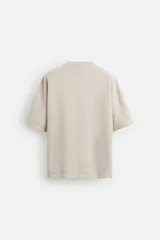 Camiseta color gris verdoso de punto tejido en hilatura de algodón, con cuello redondo, manga corta, efecto lavado y acabados irregulares.