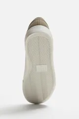 Zapatillas blancas de cuero sintético con cordones, forro interior y plantilla color beige.