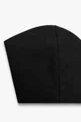Top bandeau negro con escote corazón, hombros descubiertos y cierre trasero con ganchos metálicos.