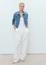 Chaqueta de denim celeste de corte cropped, con cuello camisero, cierre frontal con botones, mangas largas con puños abotonados y dos bolsillos de parche con solapa en el pecho.