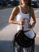 Bolso de hombro tipo boho, color bordó, confeccionado en gamuza con tachas plateadas y flecos largos. Tiene correa doble para usar al hombro o cruzado, forro interior y bolsillo interno.