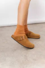 Zuecos de cuero color beige, con diseño clásico y hebilla regulable. Cuentan con plantilla anatómica y suela de corcho.