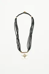 Collar corto con múltiples hilos de mostacillas negras, dije central metálico con forma de flor y barra horizontal.