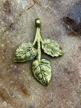 Dije de bronce con forma de rama con tres hojas.
