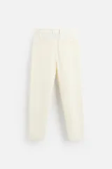 Pantalón color crudo de tejido con textura de rizo, corte relaxed fit, con cintura elástica, bolsillos frontales y traseros, cierre frontal con cremallera y botón.