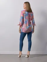 Camisa estampada con hojas en tonos celeste, naranja y verde. Tiene cuello con solapa, abertura central con botones, bolsillos aplicados en la parte delantera y mangas 3/4 con lazo.
